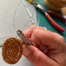 Load image into Gallery viewer, Hand using wire cutters on brown seed beads coiled into a beaded sunflower centre
