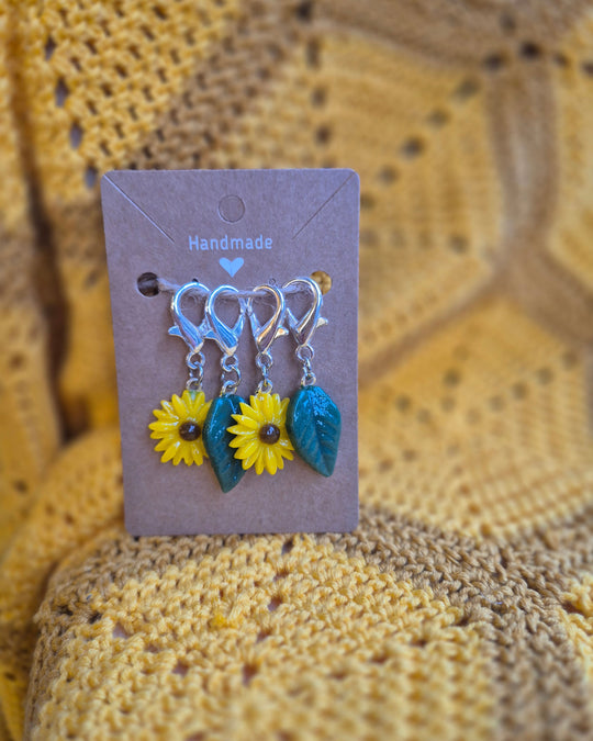 Handmade glass sunflower and leaves stitch markers by Gobblin Glass on a card