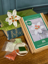 Load image into Gallery viewer, Contents of the lily beaded flower kit: orange, white and green seed beads, wire and instructions.