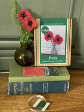 Load image into Gallery viewer, Contents of the poppy beaded flower kit: red and black seed beads, wire and instructions.
