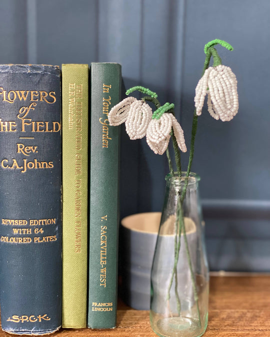 Beaded snowdrop flowers displayed in a small vase.