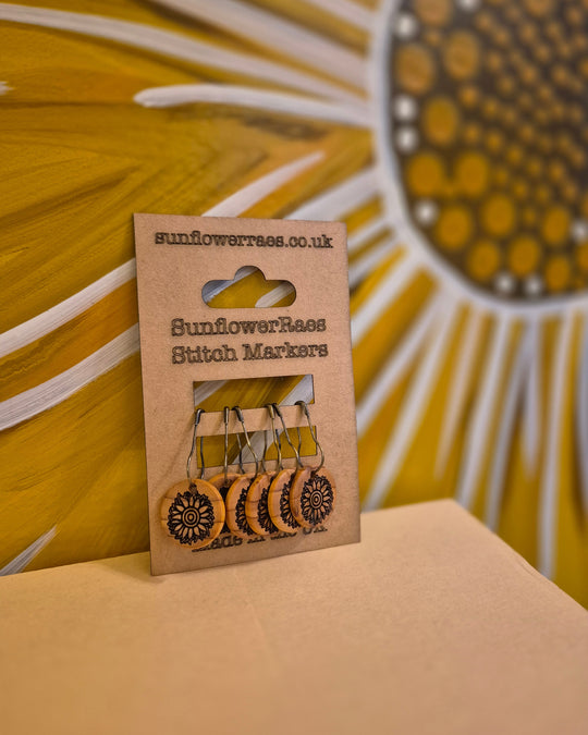 Sunflower Raes handturned yew wooden stitch markers by Tom Dyson on a kraft card pack