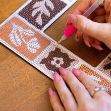 Load image into Gallery viewer, Close-up of a hand using the pink applicator pen to place gems on the Tuscan Tiles diamond painting mirror frame