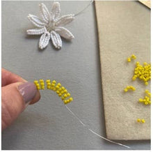 Load image into Gallery viewer, Threading yellow seed beads onto wire to make the centre of a beaded daisy
