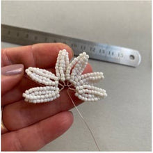 Load image into Gallery viewer, Hand holding white beaded daisy petals on wire next to a ruler for size
