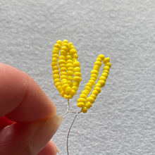 Load image into Gallery viewer, Close-up of yellow seed beads threaded onto wire to form beaded sunflower petals held in a hand
