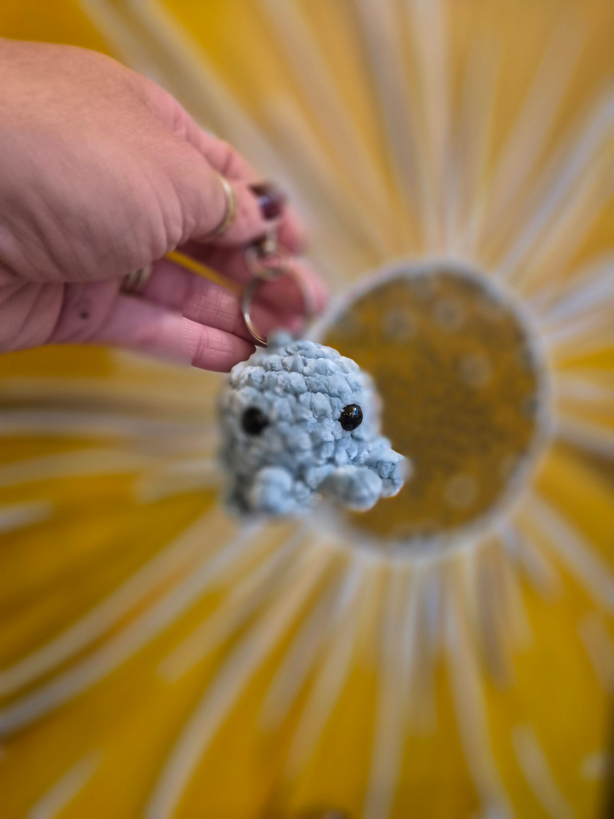 Blue crochet octopus keyring held in a hand, by Gobblin Glass