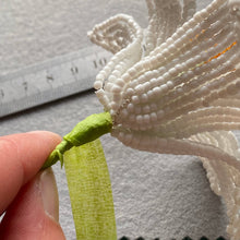 Load image into Gallery viewer, Contents of the lily beaded flower kit: orange, white and green seed beads, wire and instructions.
