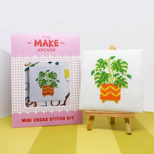 Load image into Gallery viewer, Monstera mini cross stitch kit in its pink Make Arcade envelope next to the finished stitching on a mini easel
