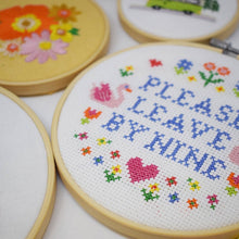 Load image into Gallery viewer, Close-up of the Please Leave by Nine large cross stitch in a wooden hoop with colourful flowers and hearts
