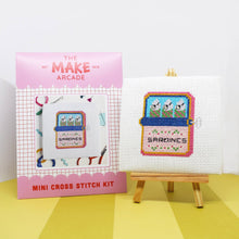 Load image into Gallery viewer, Make Arcade mini cross stitch kit envelope beside a finished sardines cross stitch on a mini easel

