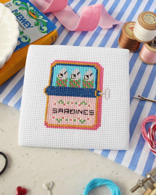 Sardines mini cross stitch kit by The Make Arcade, a finished stitched sardine tin on white Aida fabric