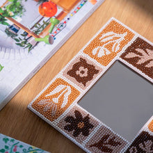 Load image into Gallery viewer, Close-up of diamond painting gems on a Tuscan Tiles mirror frame with brown and cream floral tiles
