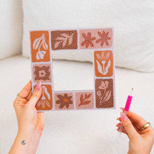 Load image into Gallery viewer, Hands holding a Tuscan Tiles diamond painting mirror frame in progress with a gem applicator pen
